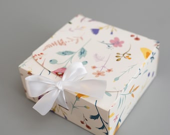 Caja de regalo con estampado floral y lazo de satén, ideal para bodas y despedidas de soltera.