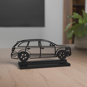 Könnte beinhalten: Schwarze Skulptur eines Kombi-Autos. Räder und Fenster sind sichtbar. Die Skulptur steht auf einem rechteckigen Sockel. Hergestellt aus einem festen Material, ist sie für die Präsentation geeignet.