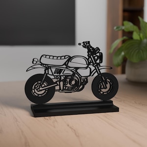 Könnte beinhalten: Schwarze Motorradskulptur mit detailliertem Design, einschließlich Rädern, Sitz und Lenker. Das Motorrad ist auf einem rechteckigen Sockel montiert. Die Skulptur besteht aus einem festen Material und eignet sich zur Präsentation.