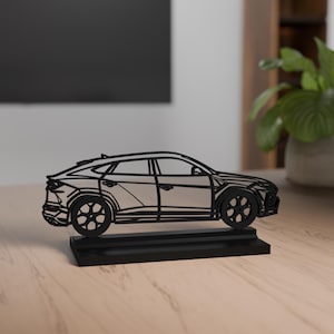 Könnte beinhalten: Eine schwarze, stilisierte Autoskulptur. Das Auto ist im Strichzeichnungsstil dargestellt, mit sichtbaren Rädern und Fenstern. Es steht auf einem rechteckigen Sockel und erzeugt eine moderne, minimalistische Ästhetik. Die Skulptur ist wahrscheinlich ein dekorativer Gegenstand.