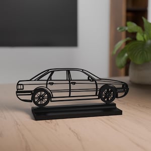 May include: A black metal car sculpture. The sedan car has detailed wheels and windows, mounted on a rectangular base. The sculpture is a minimalist design, suitable for home decor.