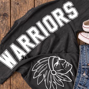 May include: A charcoal gray t-shirt featuring the word WARRIORS in large white block letters and a white line art graphic of a person wearing a feathered headdress. The shirt is paired with blue denim jeans and white canvas sneakers.