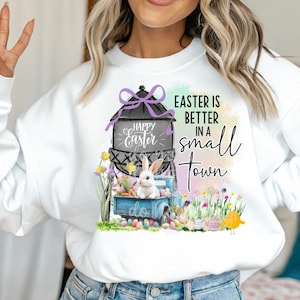 May include: White sweatshirt with a graphic of a blue truck with a bunny rabbit, a water tower with the text "Happy Easter", and the text "Easter is better in a small town".