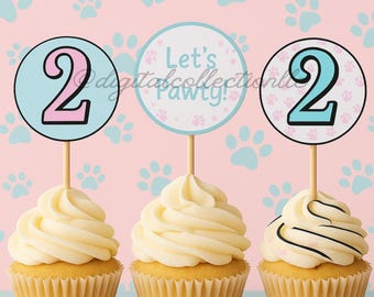 Puede incluir: Tres cupcakes decorados con adornos temáticos de huellas de patas azules y rosas. Los adornos dicen "Let's Pawty!" y "2".