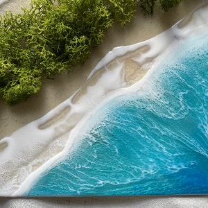 Pu&ograve; includere: Opera d'arte in resina raffigurante una scena di spiaggia con onde turchesi, schiuma bianca e una riva sabbiosa. &Egrave; incluso del muschio verde. Il pezzo &egrave; un oggetto decorativo unico.