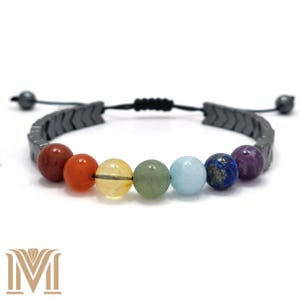 May include: A black hematite bracelet featuring seven chakra beads. The beads are red, orange, yellow, green, blue, indigo, and violet. The bracelet is adjustable with a sliding knot.