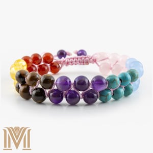May include: A double-strand bracelet with a variety of coloured beads. The bracelet features beads in yellow, red, brown, purple, turquoise, and pink. The beads are strung on a pink cord, creating a colourful accessory.