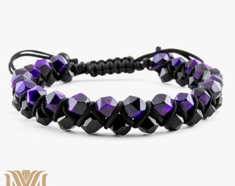 May include: A bracelet with faceted purple and black beads strung on black cord. The bracelet has an adjustable closure and a double-strand design. The beads are arranged symmetrically, creating a contrast of colours and textures. The bracelet is suitable for a wrist size of approximately 15-20 cm.