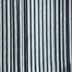 May include: A close-up of a stack of gray metal rods. The rods are arranged in a vertical pattern and are all the same size.
