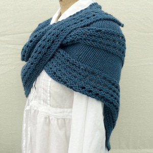 May include: A blue knitted shawl with a lacy pattern. The shawl is draped over a white shirt.