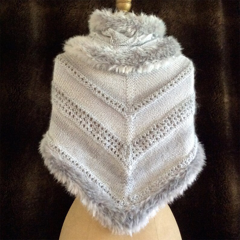 May include: A gray knitted shawl with a faux fur trim. The shawl has a delicate lace pattern and a high collar.