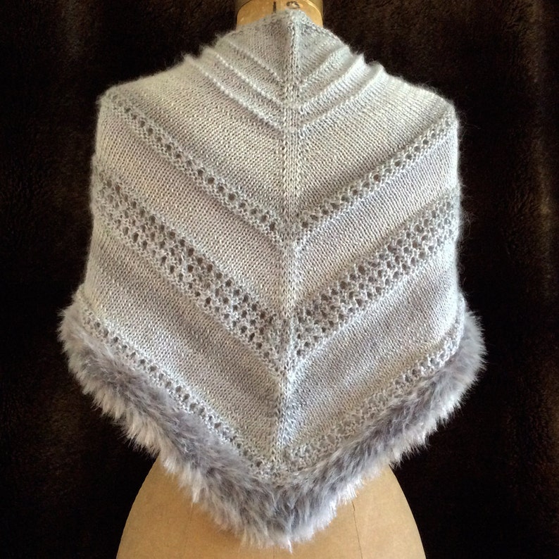 May include: A gray knitted shawl with a lacy pattern and a faux fur trim.