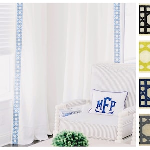 May include: White curtains with blue trim, a white chair with blue and white striped upholstery, a white pillow with the monogram "MFP" in blue embroidery, and a green plant in a white pot. The chair is in front of a window with white blinds. The image also shows four different fabric samples with a geometric pattern in black, yellow, blue, and gray.