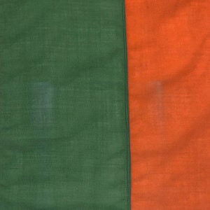 Puede incluir: Primer plano de una tela con dos secciones, una verde y otra naranja, separadas por una costura negra.