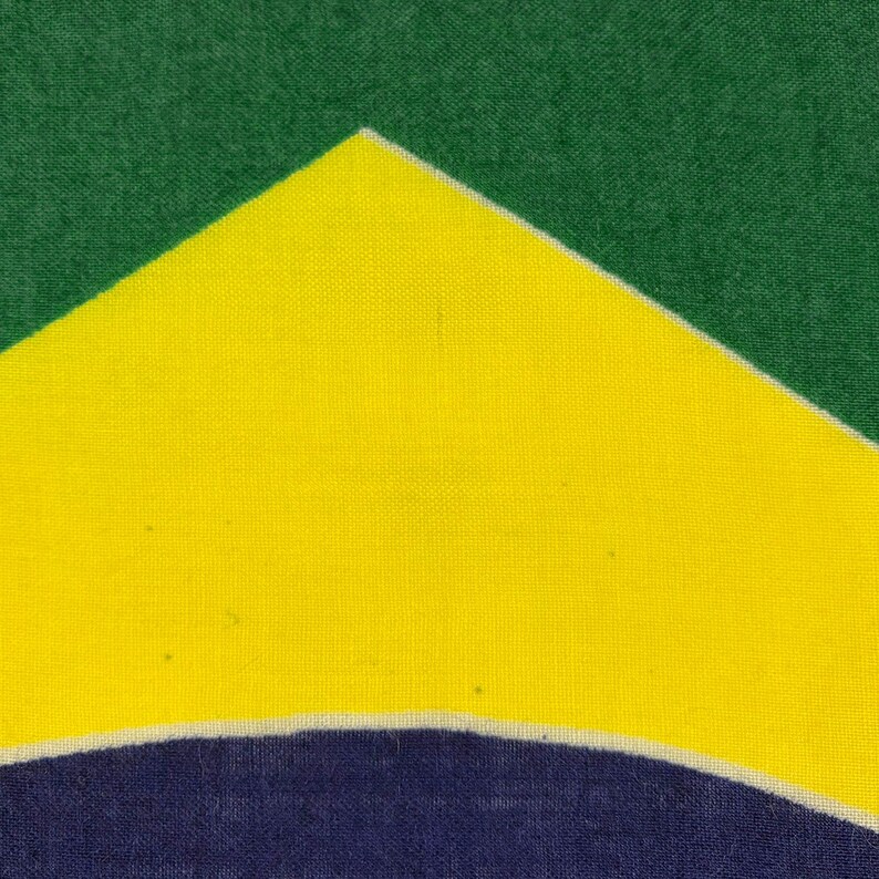 Pode incluir: Close-up da bandeira brasileira, com um fundo verde e um losango amarelo no centro. Um globo azul com estrelas brancas &eacute; vis&iacute;vel dentro do losango amarelo.
