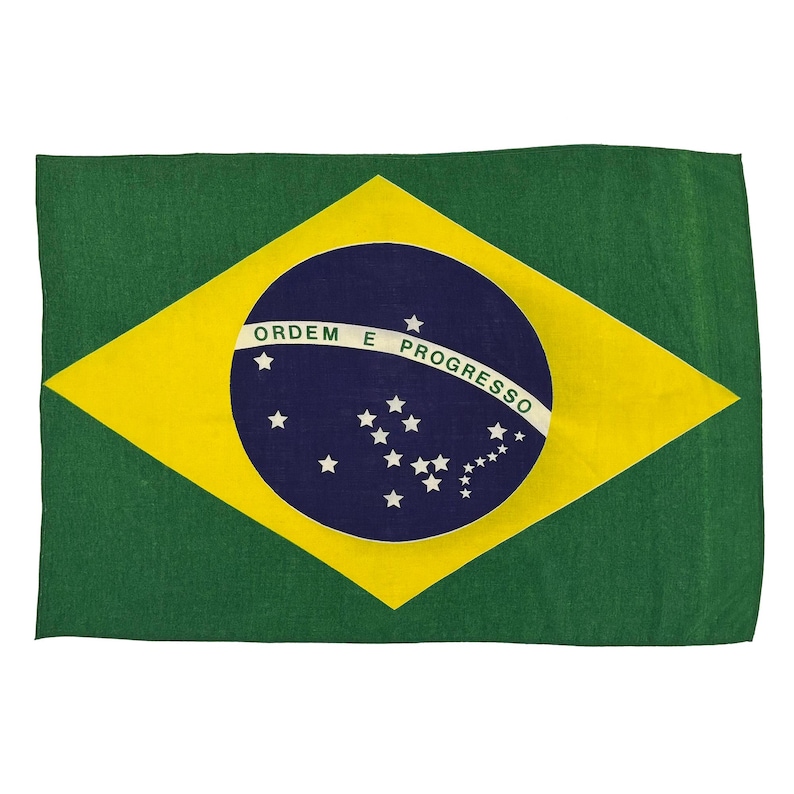 Pode incluir: Uma bandeira brasileira retangular. Apresenta um fundo verde, um losango amarelo e um c&iacute;rculo azul no centro. O c&iacute;rculo azul cont&eacute;m estrelas brancas e as palavras "Ordem e Progresso".
