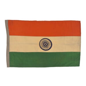 May include: A rectangular flag of India, featuring horizontal bands of orange, white, and green. The white band contains a navy blue Ashoka Chakra, a 24-spoke wheel. The flag has a gray border on the left side.