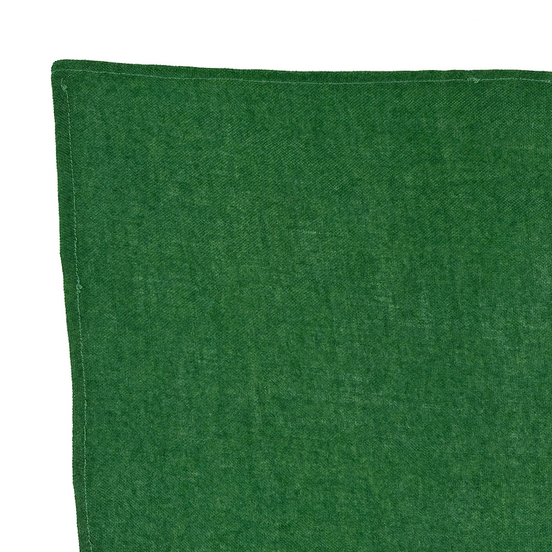 Pode incluir: Um close-up de um tecido verde com uma textura tecida vis&iacute;vel. O tecido &eacute; de um tom verde s&oacute;lido e profundo, com um brilho sutil. As bordas s&atilde;o cuidadosamente bainhadas com uma costura fina.