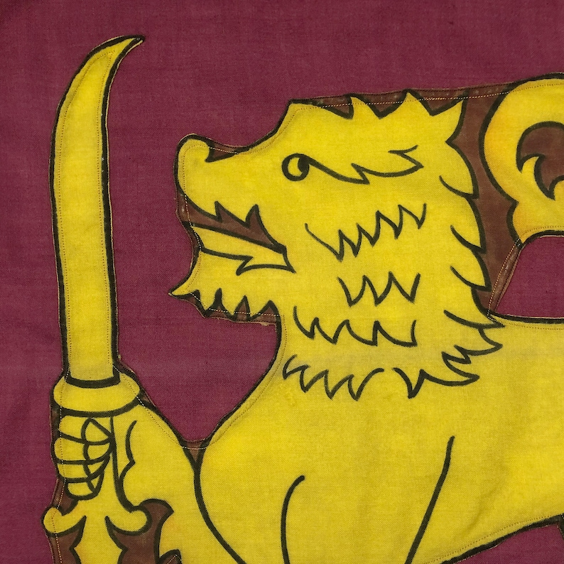 Puede incluir: Un le&oacute;n amarillo con una espada marr&oacute;n en su pata, sobre un fondo marr&oacute;n. El le&oacute;n est&aacute; mirando hacia la izquierda y tiene una melena marr&oacute;n. La espada est&aacute; apuntando hacia arriba.