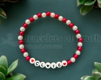 May include: Red and white beaded bracelet with the letters "CL16" and two red hearts. The bracelet is handmade and says "Bracelets of Truth" on the tag.
