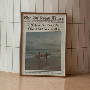 May include: A potted palm tree sits in a white tiled room with a framed newspaper clipping that reads "The Gulfcoast Times, Locals Thank God For A Single Wave".