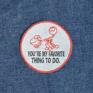 Puede incluir: Un parche bordado blanco y rojo con un dibujo de un hombrecito de palo empujando una carretilla. El texto en el parche dice "You're my favorite thing to do."