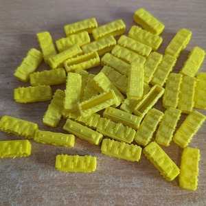 May include: A pile of yellow plastic building blocks. The blocks are rectangular and have a textured surface.