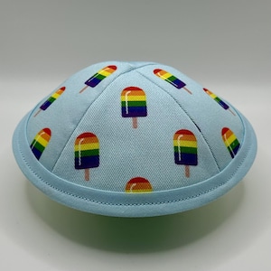 May include: A light blue kippah with a pattern of rainbow popsicles.