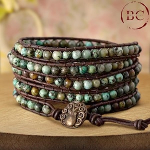 May include: A multi-strand leather wrap bracelet with turquoise beads and a decorative metal clasp. The bracelet is brown and features a variety of turquoise shades.