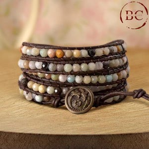 May include: Multi-strand leather wrap bracelet with a variety of colorful gemstone beads and a decorative metal button closure.