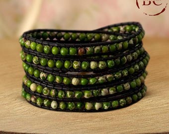 May include: A multi-strand bracelet featuring green and white jasper beads with black leather wrappings.