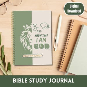Könnte beinhalten: Ein grünes und weißes Spiralbuch mit dem Text "Be Still and Know That I Am God" und einem Löwen mit einer Krone auf dem Kopf. Das Buch ist mit "Bible Study Journal" beschriftet.