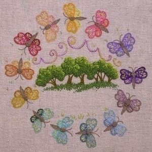 May include: Embroidered design featuring a circle of colourful butterflies surrounding a group of green trees with a garland of swirls above them.
