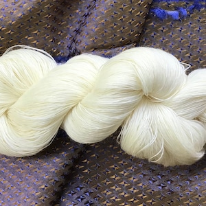 Peut inclure: Une pelote de fil de soie blanc, une fibre douce et délicate, idéale pour le tricot ou le crochet.