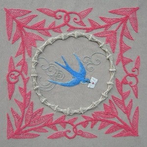 May include: Embroidered artwork featuring a blue bird carrying a small white envelope, flying within a circular frame of white thread. The frame is surrounded by a pink floral design.