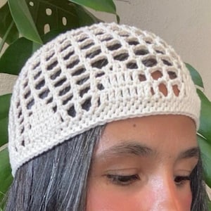 May include: A white crocheted hat with a grid pattern. The hat is worn on a person's head.