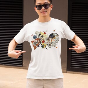May include: A white t-shirt featuring a colourful abstract design with geometric shapes, lines and circles. The design is reminiscent of a modern art painting.