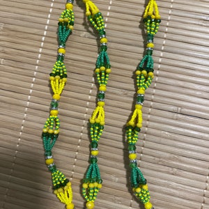 May include: Three beaded bracelets in yellow, green, and silver. The bracelets feature a repeating pattern of yellow and green bead clusters, linked by smaller beads. Each bracelet has a silver clasp.