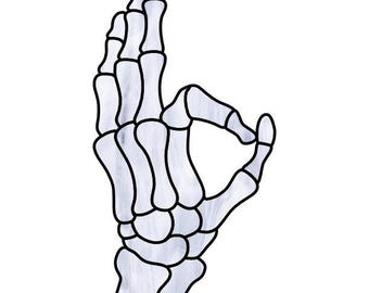 A skeleton hand with long, thin bones forms the "OK" gesture, the thumb and index finger creating a circle, other fingers relaxed.
