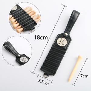 May include: A black leather golf tee holder with a handle, measuring 18cm long and 3.5cm wide, holds several wooden golf tees. A single tee, 7cm long, is shown separately. The holder features a metal emblem with the letters "B" and "S" crossed with a golf club.
