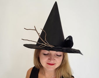 May include: Black witch hat with a wide brim and a tall, pointed crown. The hat is decorated with a small, black bird, feathers, and twigs. A festive accessory for Halloween or costume parties.