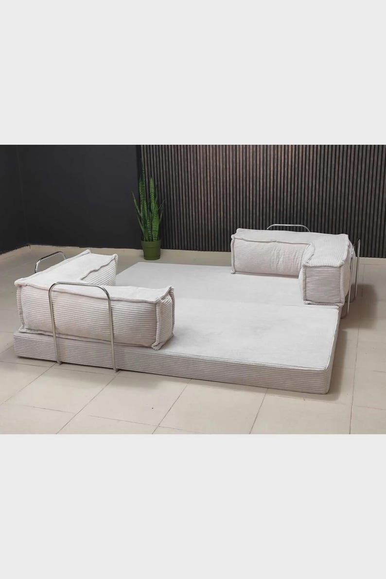 Pu&ograve; includere: Un set di divani modulari in velluto a coste di colore chiaro. Il set comprende una grande base rettangolare e diversi componenti quadrati imbottiti con telai in metallo. Il divano &egrave; progettato per composizioni versatili e sedute confortevoli.