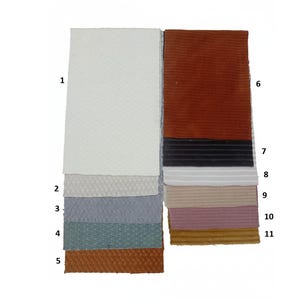 Pu&ograve; includere: Una collezione di undici campioni di tessuto in vari colori e texture. I campioni includono tonalit&agrave; bianche, grigie, blu e marroni, con un mix di superfici lisce e strutturate. La disposizione mostra una gamma di materiali per il design e l'artigianato.