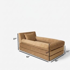 May include: A modern, tan-colored chaise lounge with a rectangular design. The lounge measures 62 inches long, 35 inches wide, and 27 inches high. It includes a small pillow and a rolled bolster. The seat is 17 inches wide and the base is 11 inches high.