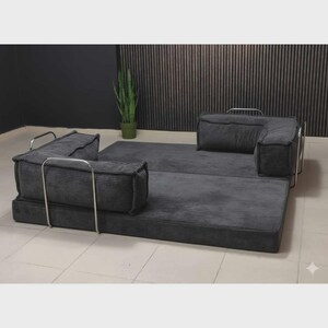 Peut inclure: Un canap&eacute; modulaire en velours c&ocirc;tel&eacute; gris avec un design minimaliste. Le canap&eacute; comprend une base rectangulaire, deux accoudoirs et deux coussins de dossier, le tout dans une couleur gris fonc&eacute;. Le cadre m&eacute;tallique ajoute une touche moderne.