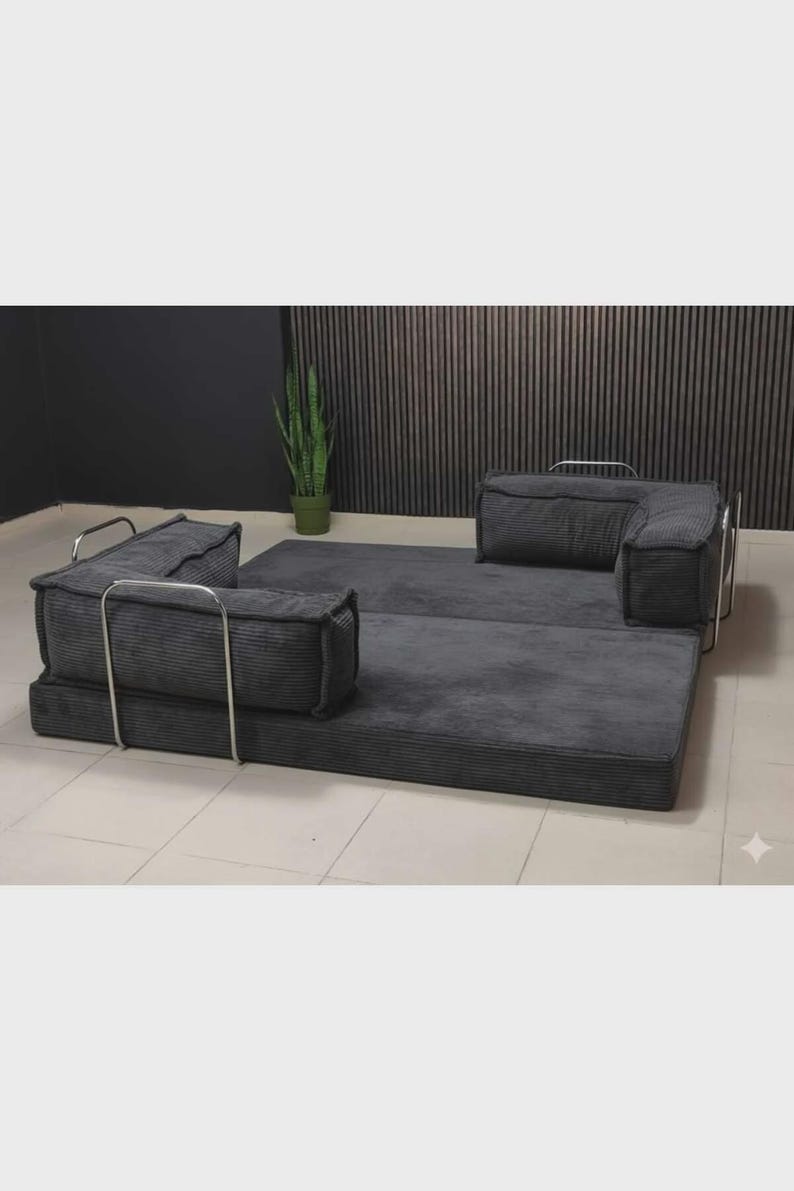 Peut inclure: Un canap&eacute; modulaire en velours c&ocirc;tel&eacute; gris avec un design minimaliste. Le canap&eacute; comprend une base rectangulaire, deux accoudoirs et deux coussins de dossier, le tout dans une couleur gris fonc&eacute;. Le cadre m&eacute;tallique ajoute une touche moderne.