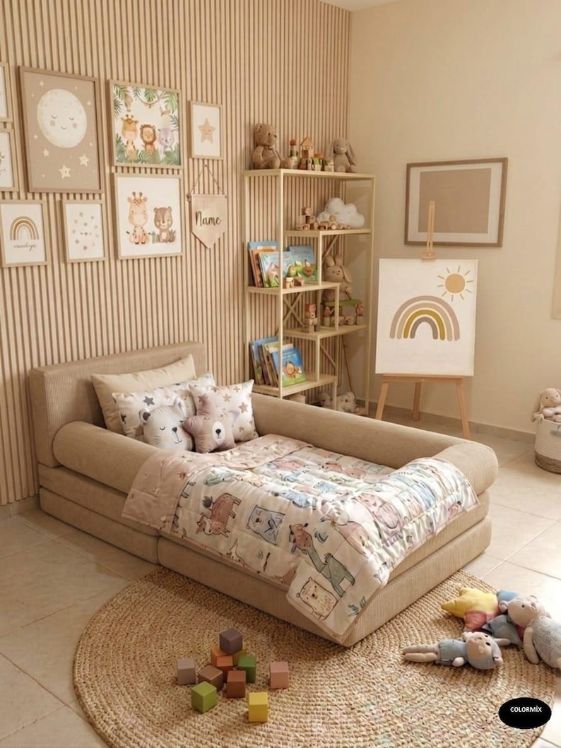 May include: A child's bedroom with a beige bed, a round woven rug, and a wooden bookshelf. The bed has a patterned quilt and pillows. Artwork with animal illustrations and a rainbow painting adorn the walls. Toys and books are arranged throughout the room.