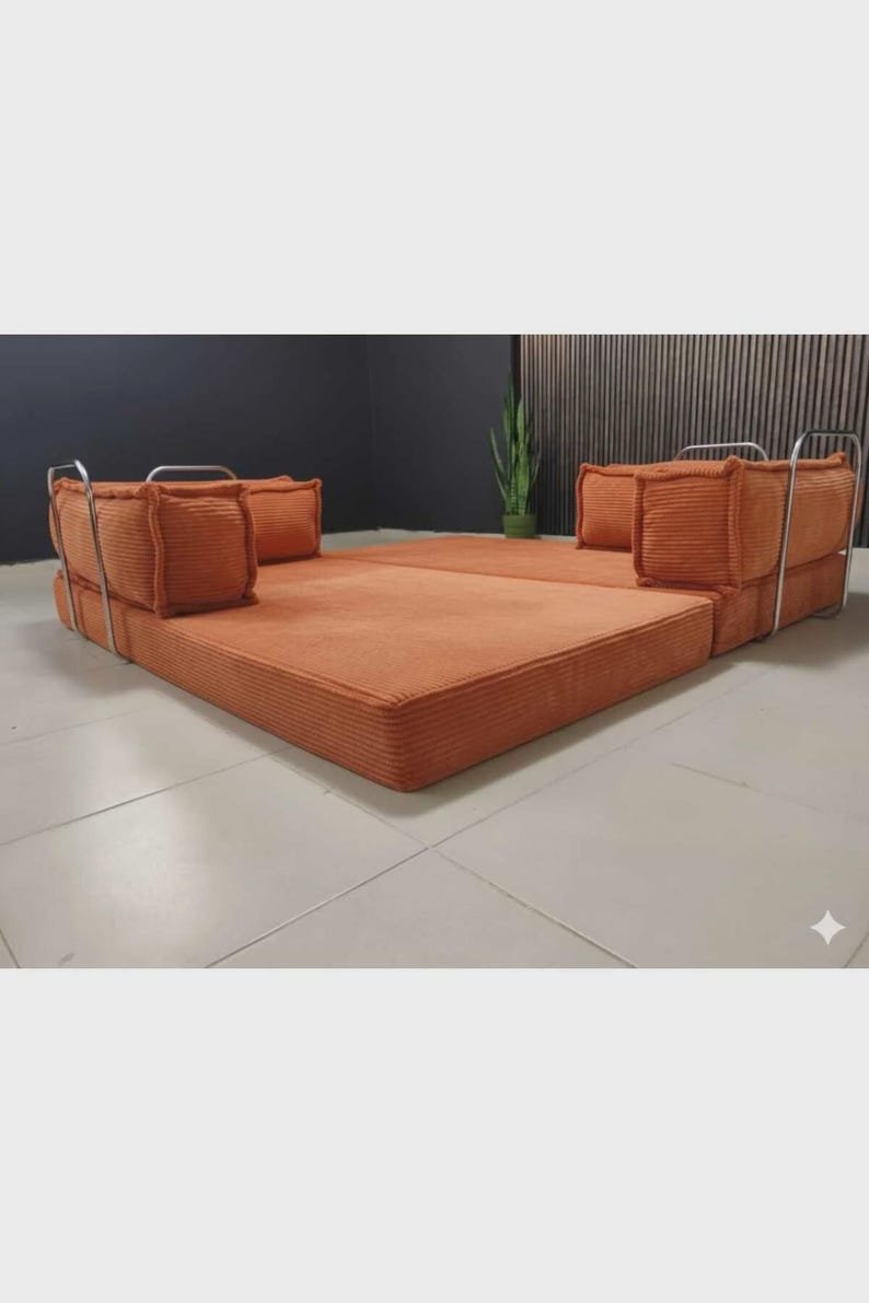 May include: An orange modular sofa with a low profile and a corduroy texture. The sofa has a rectangular base and two sections with square cushions and metal frames. The design is modern and minimalist.