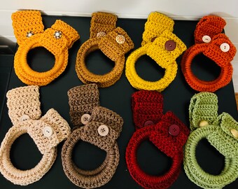 May include: Set of ten crocheted pot holders in various colors, including beige, brown, green, and red. Each pot holder features a loop for hanging and a button detail.
