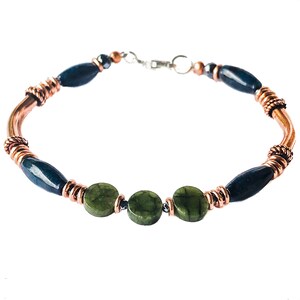 May include: A copper wire wrapped bracelet with green jade and dark blue oval beads.